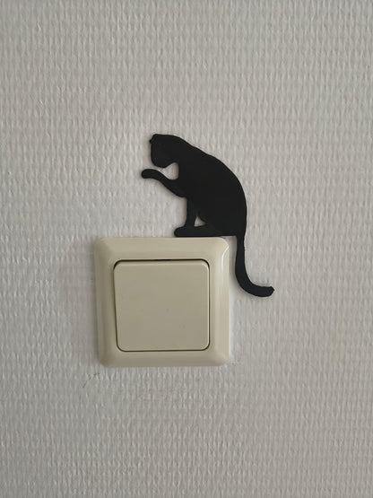 Katten lichtschakelaar decoratie van een kat die zijn pootje wast, te plaatsen aan de muur zonder boren